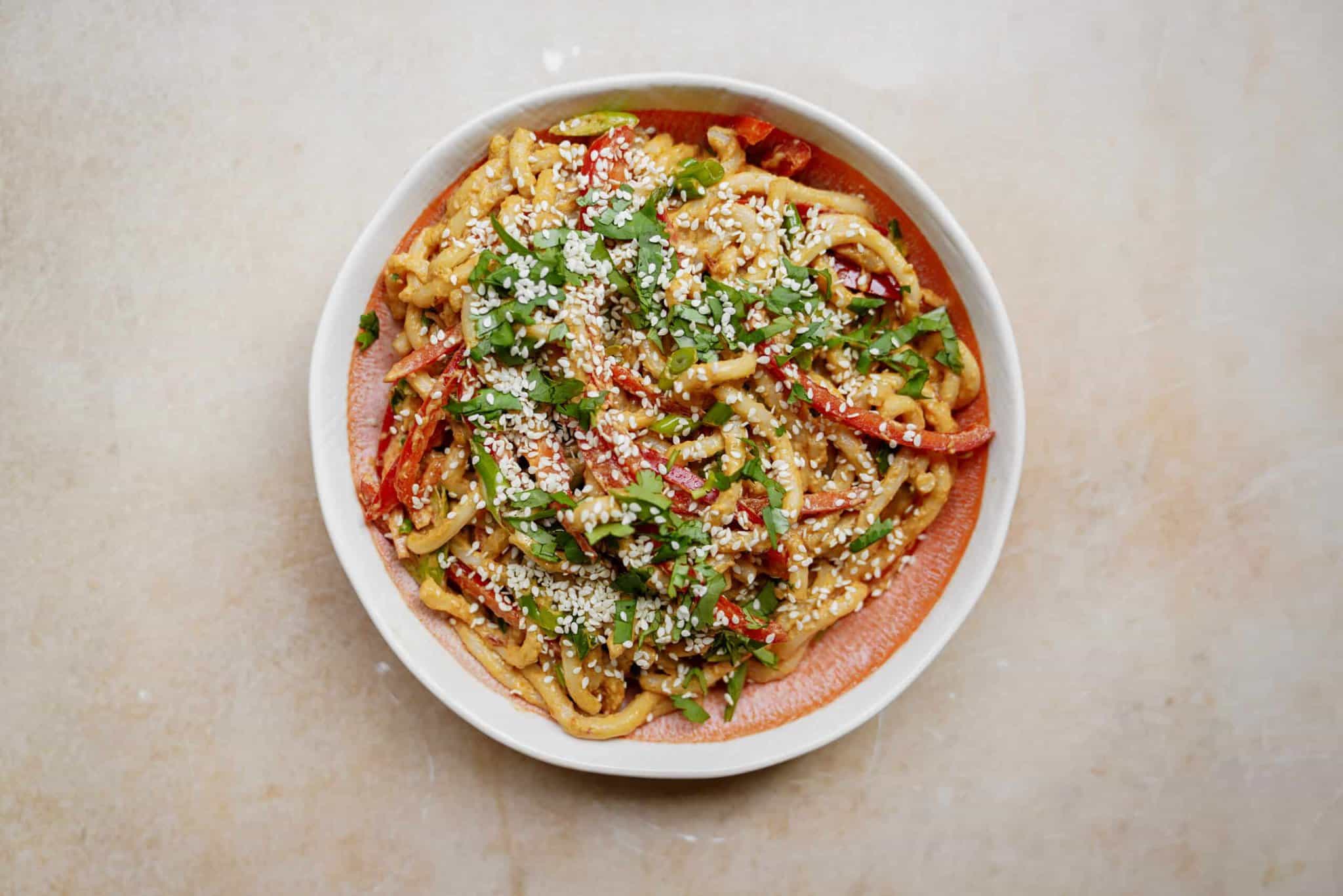 Creamy, spicy udon noodles with peanut sauce in a bowl