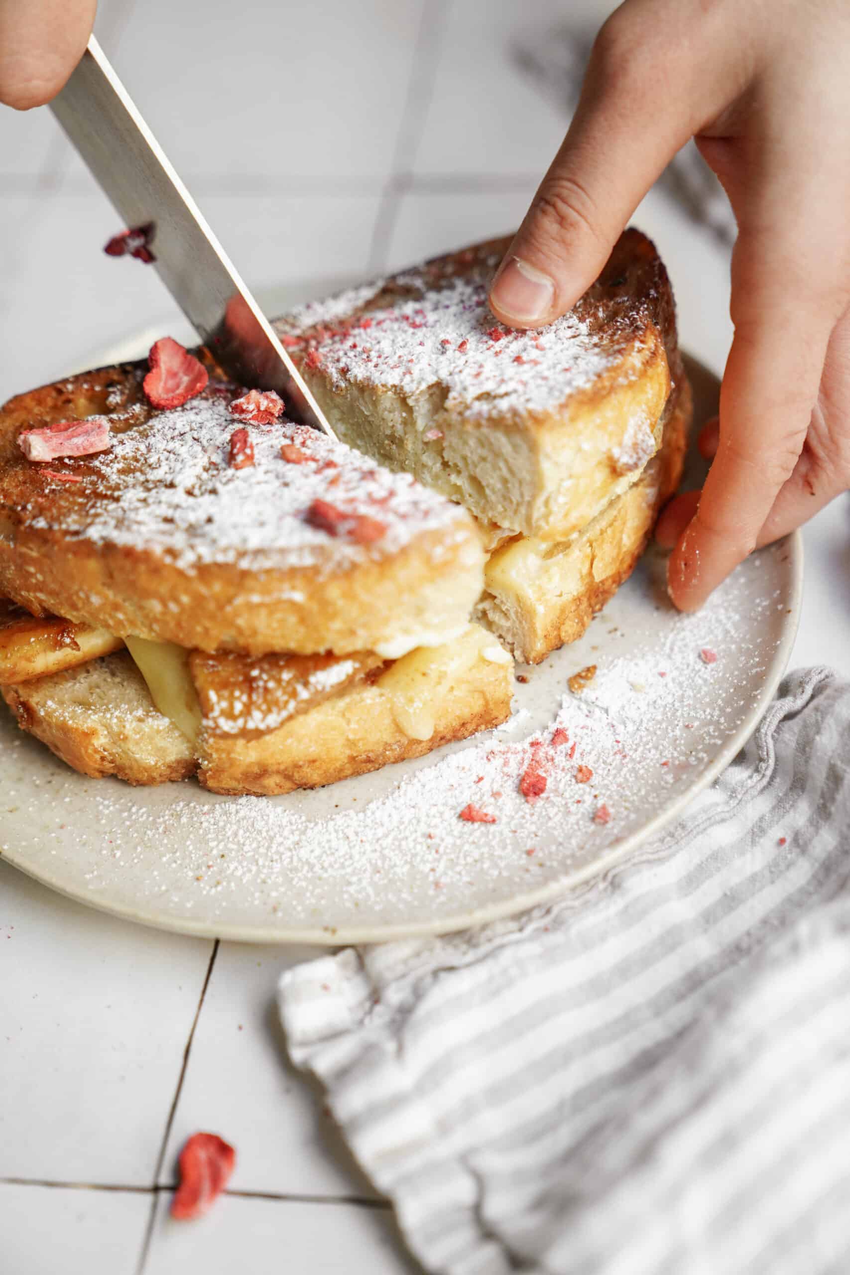 Banana fosters recipe in grilled cheese form on white plate being cut into