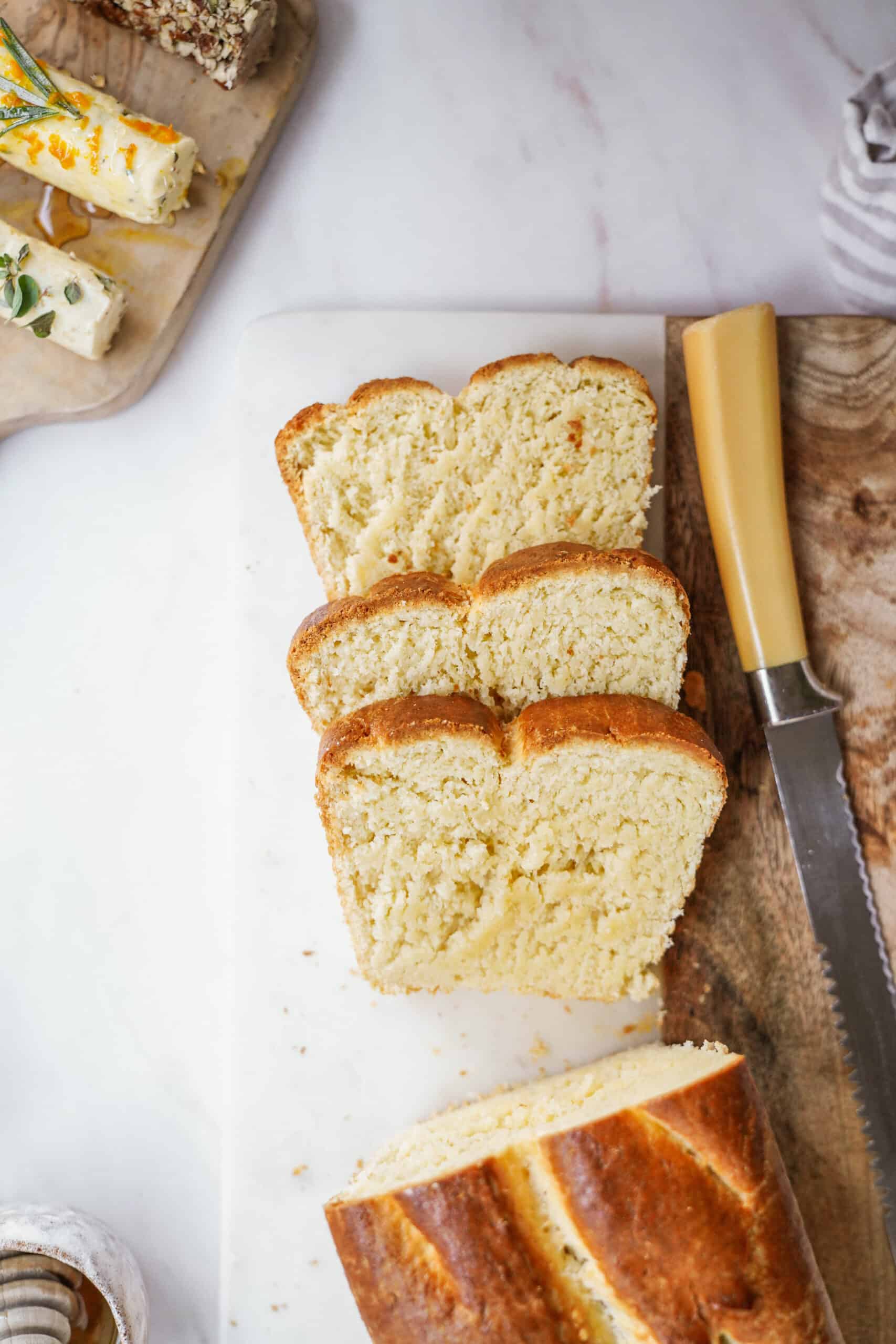 Sliced homemade bread next to compound butter on cutting board