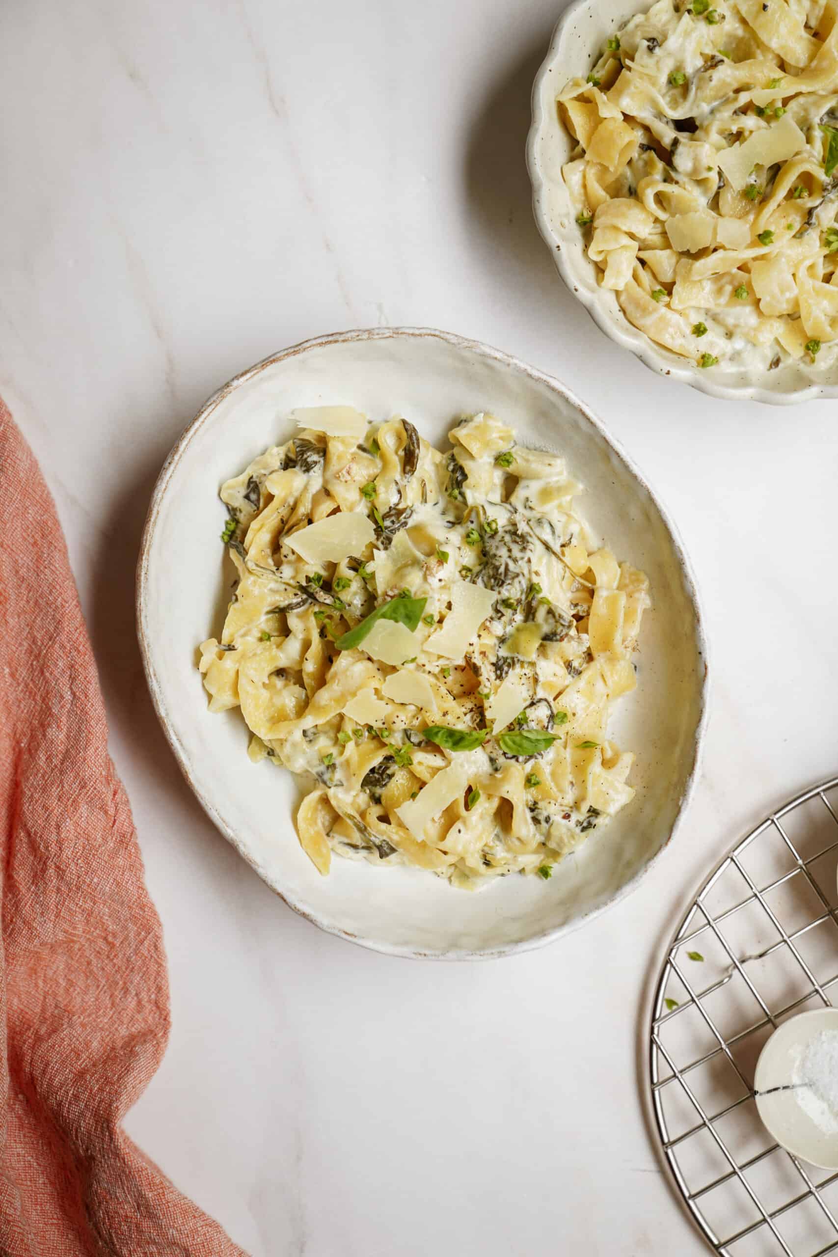 Spinach and artichoke pasta on white plates