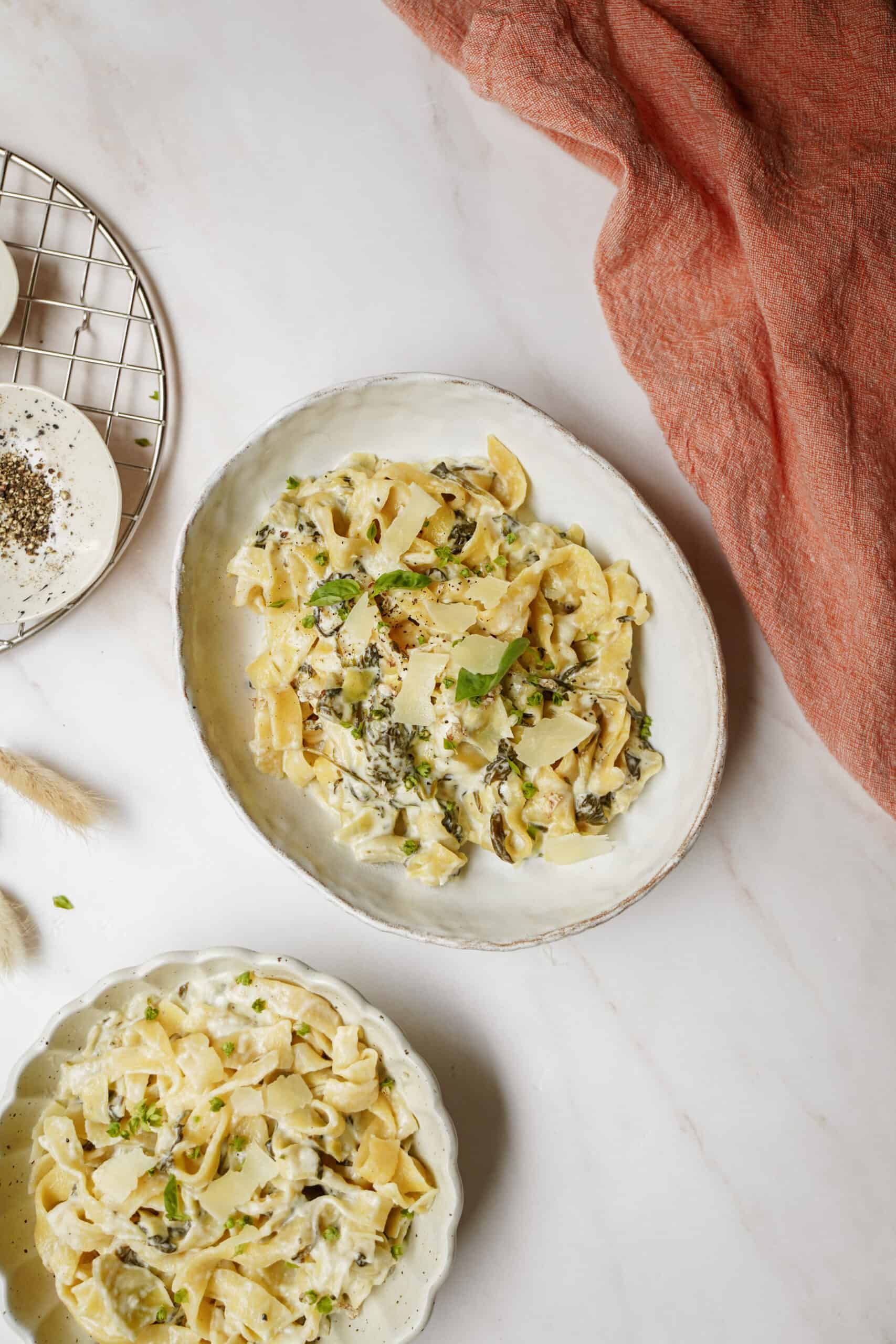 Spinach and artichoke pasta on white plates