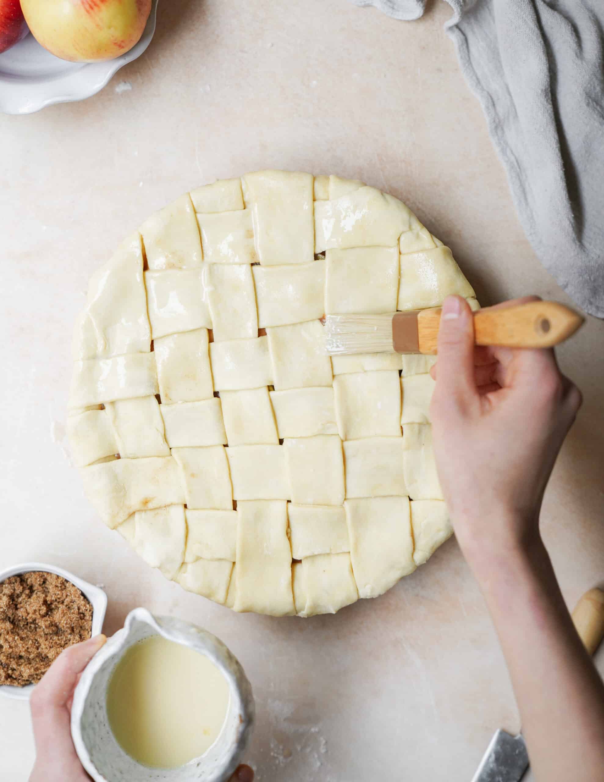 Egg wash being added to top of apple pie