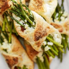 Golden puff pastries wrapped around asparagus spears and crumbled cheese, topped with a sprinkle of spices.