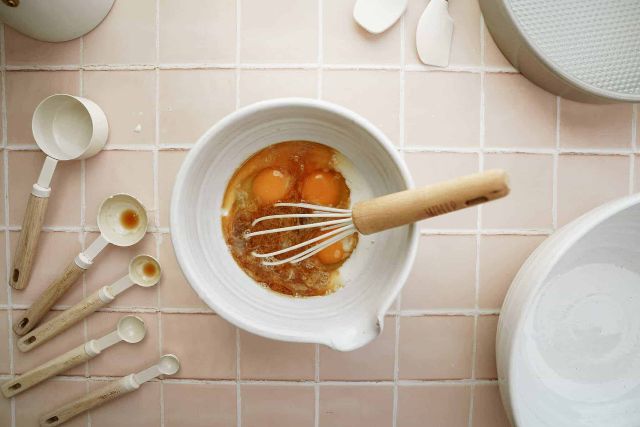 Bowl of wet ingredients for vanilla cake with a whisk in it