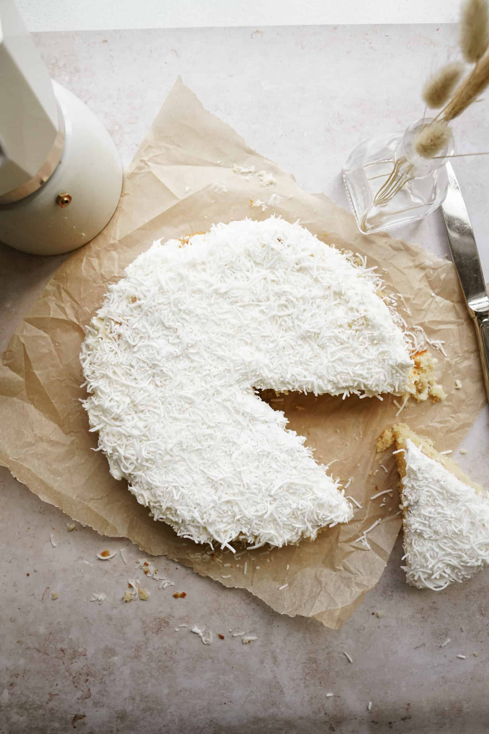 Vanilla cake with a slice out of it on a countertop