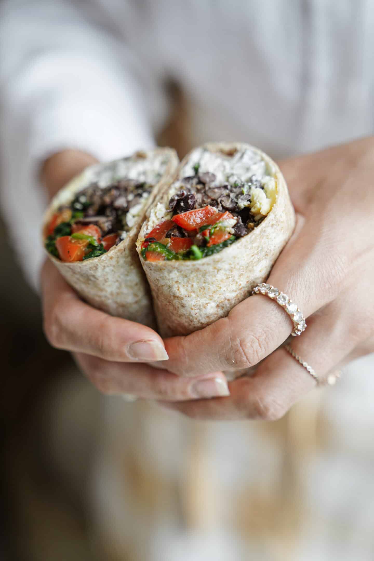 High protein breakfast burrito in someones hands