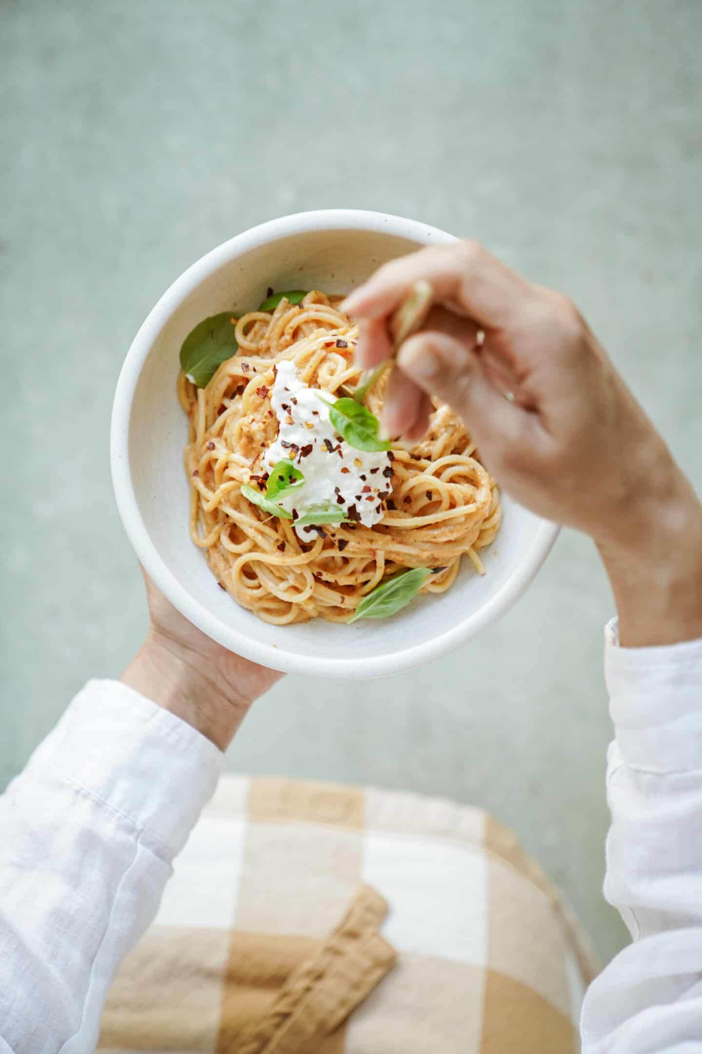 Hand swirling burrata pasta in a white bowl