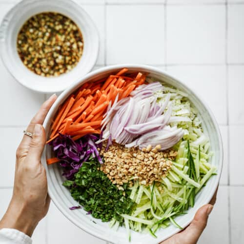 Hand holding cabbage salad in a bowl