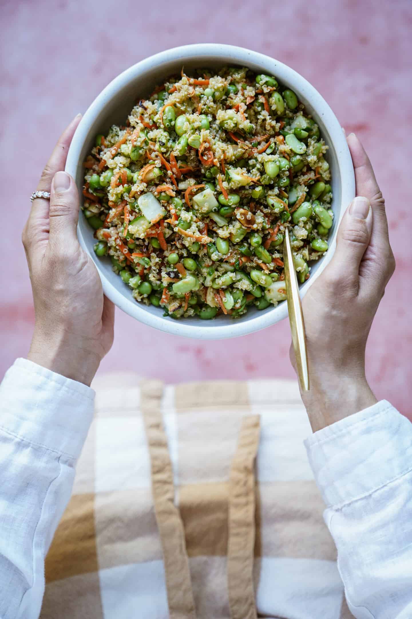 hands holding edamame salad