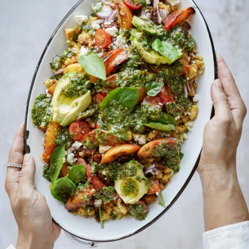 Hands holding a plater of grilled peaches salad