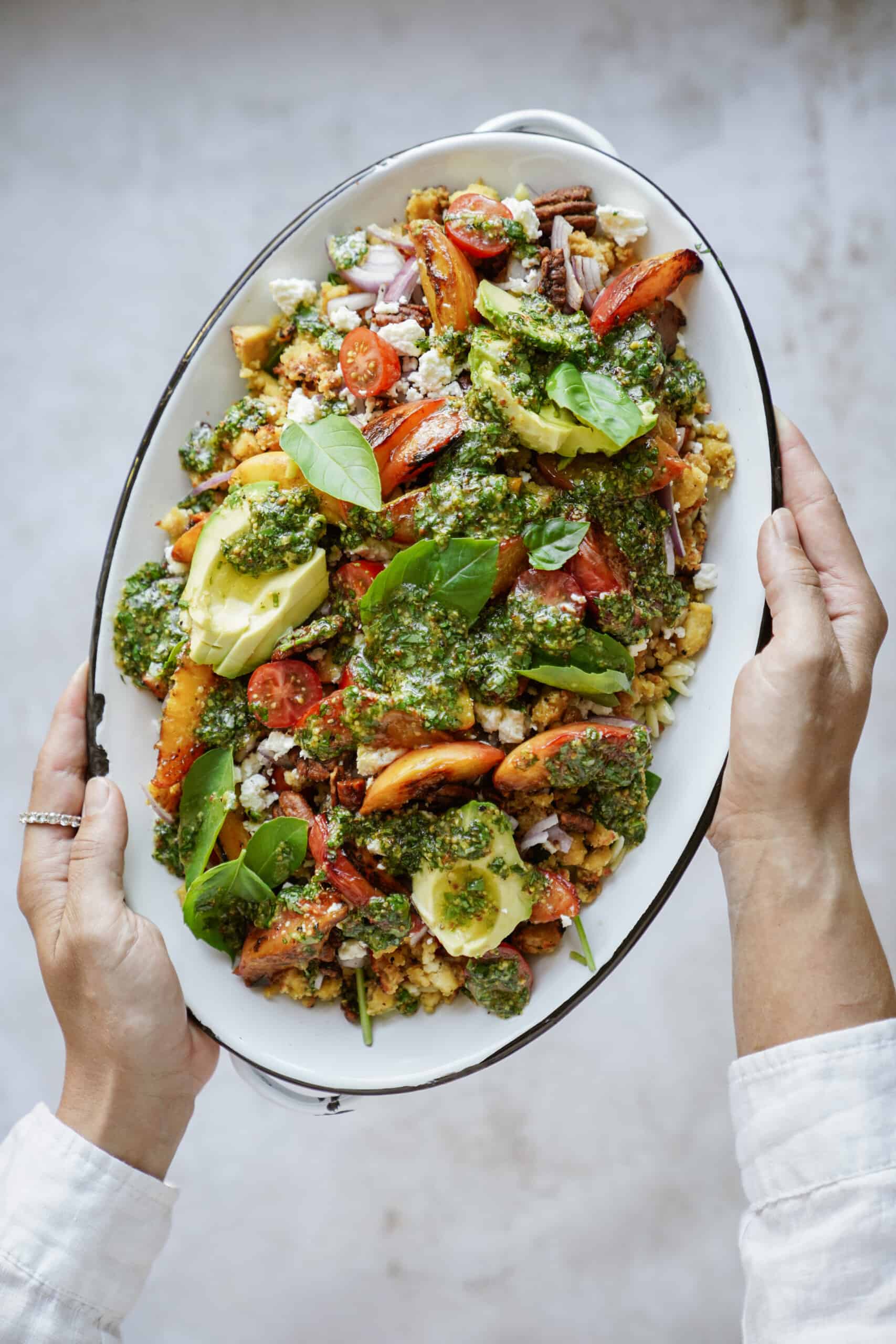 Hands holding a plater of grilled peaches salad