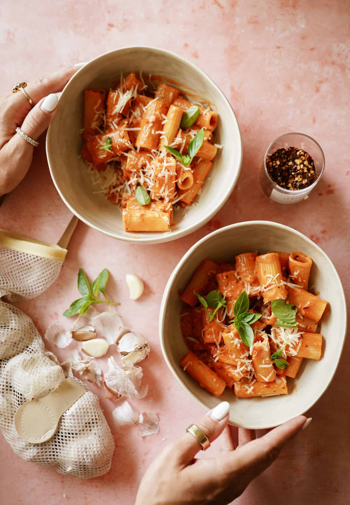 Two bowls of Gigi Hadid's vodka pasta on a counter with hands touching the bowls