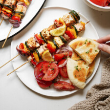 BBQ salmon kebabs on a plate with pita and tomato salad