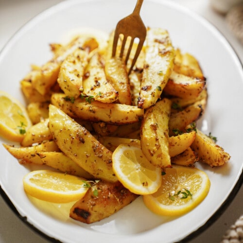 Greek Potatoes on a plate with a fork in them