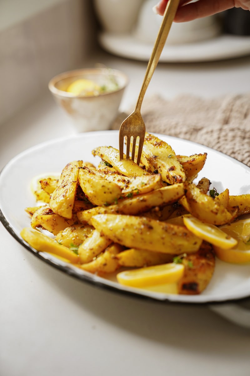 Crispy Greek potatoes with a fork in it