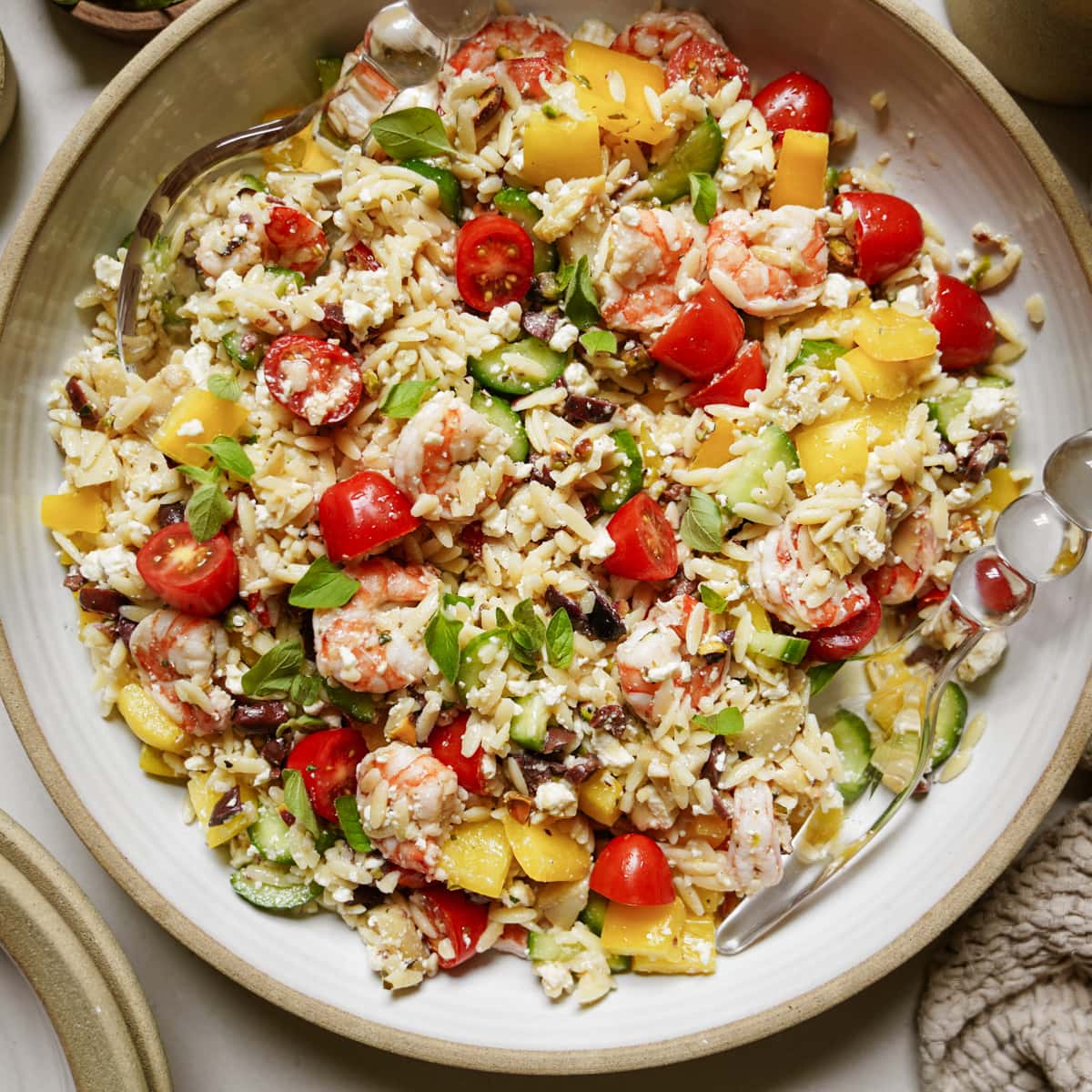 Orzo on a white serving dish full of fresh, colorful veggies 