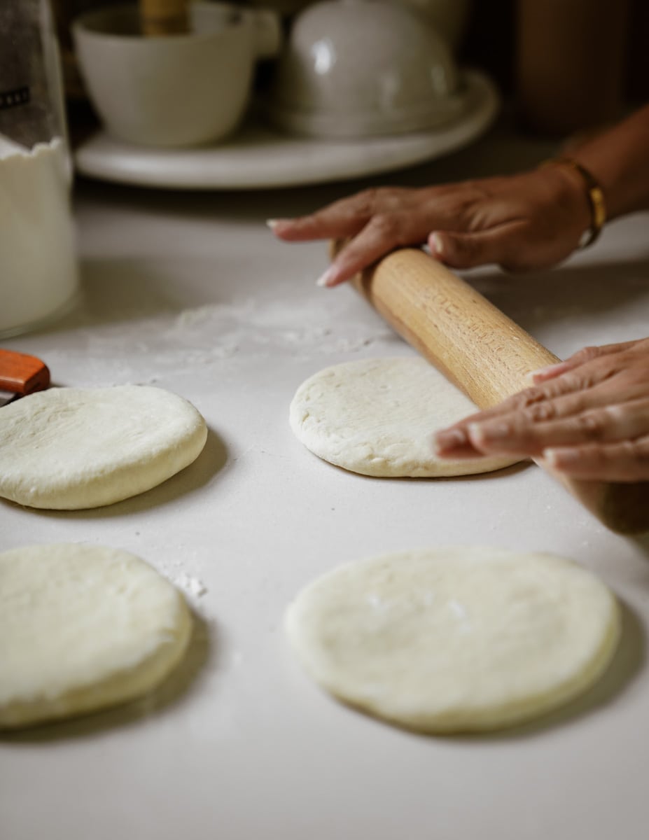 Using a rolling pin to roll out pita dough