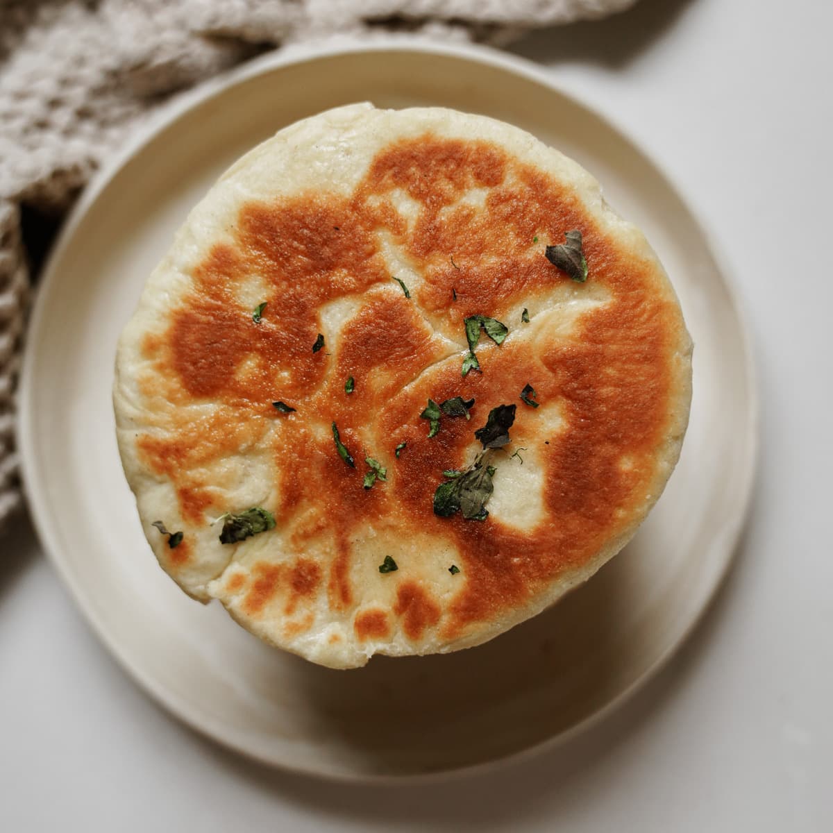 A white plate with fluffy pita bread on top