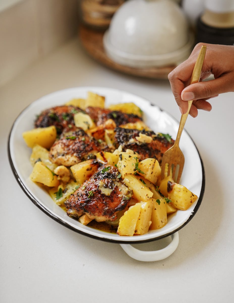 Greek chicken and potatoes in a casserole dish with a fork digging into it