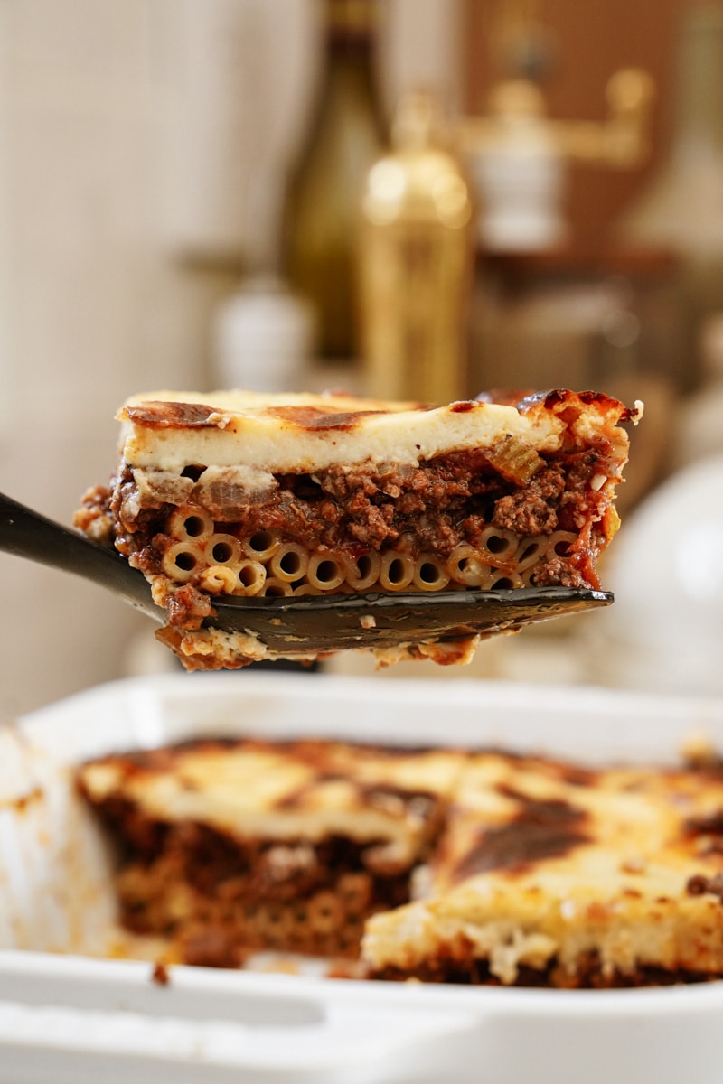 Sliced piece of pastitsio coming out of a casserole dish