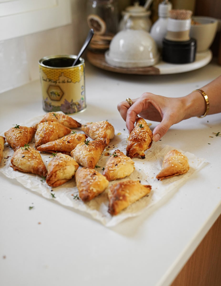 Hand grabbing tiropita of parchment paper