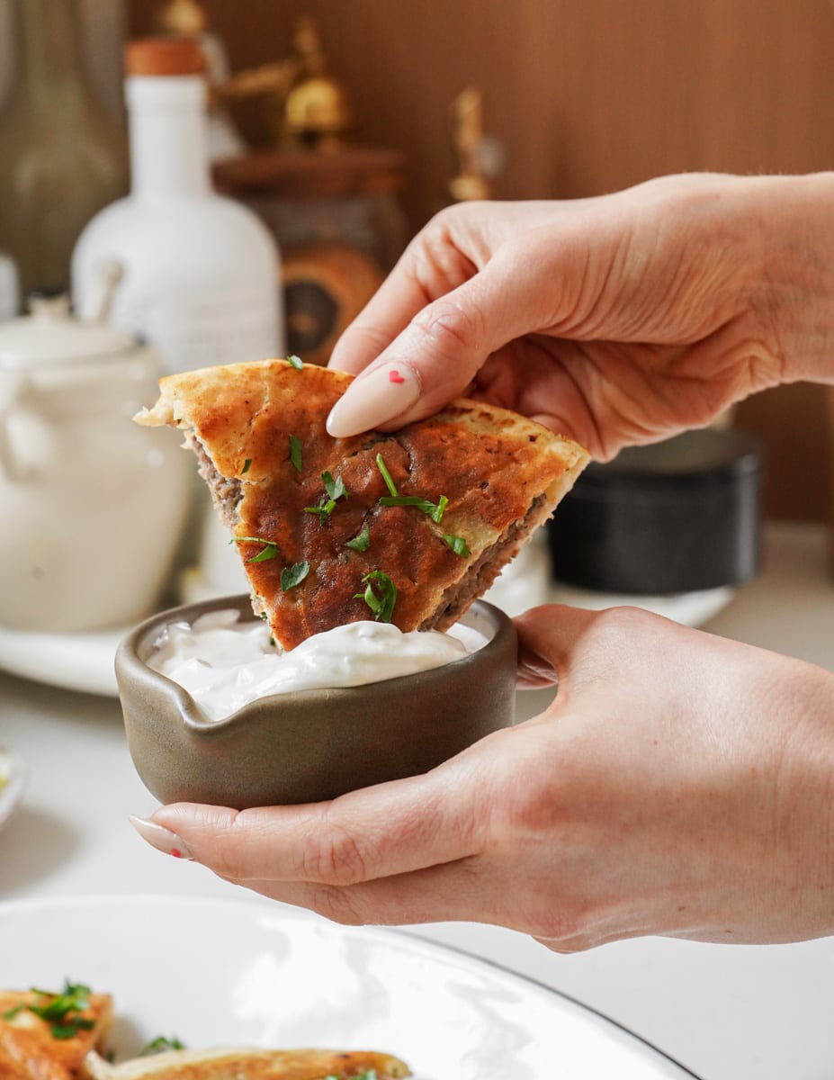 Arayes being dipped in tzatziki 