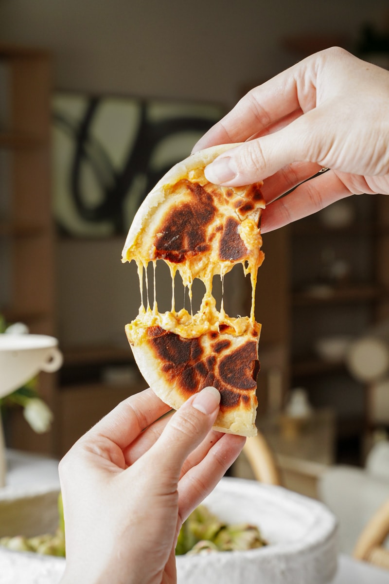 Hands pulling a part a gooey fluffy pita bread