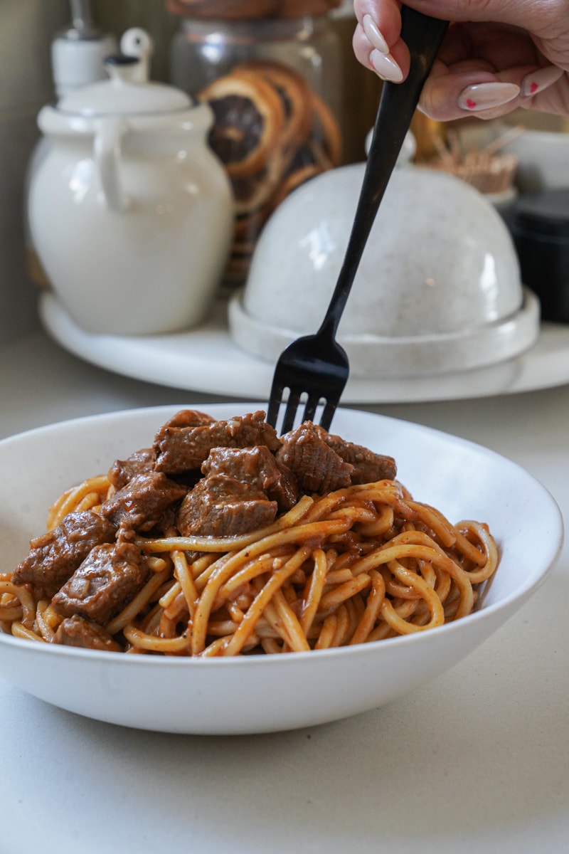 Close up of a fork spinning the noodles in a beef stew