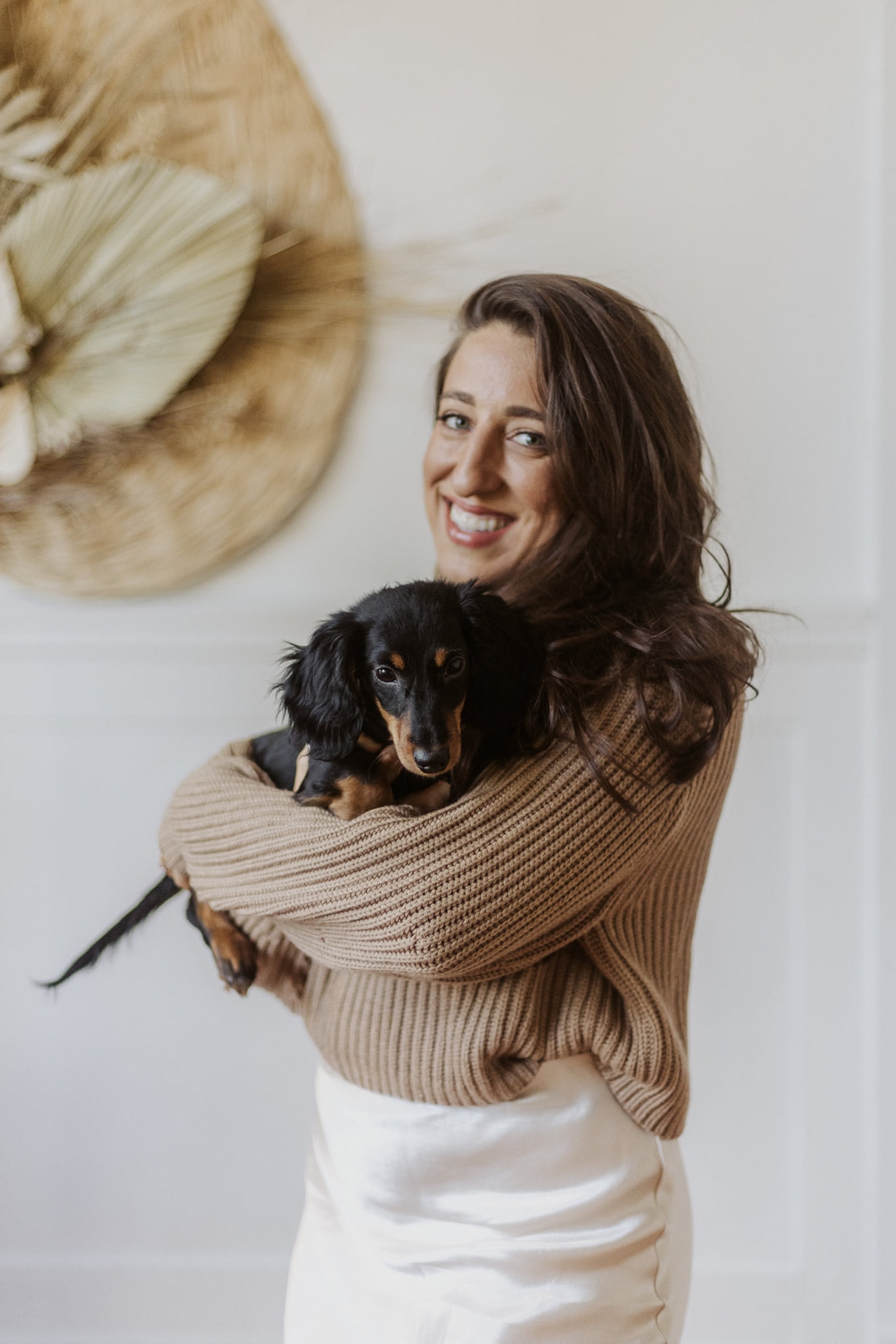 Picture of Maria in a tan top and white dress with her dog