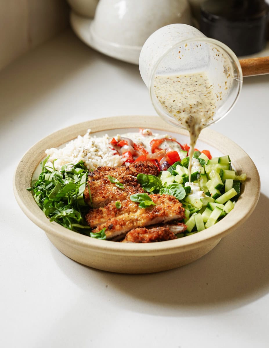 Dressing being poured on Chicken Cutlets Bowl