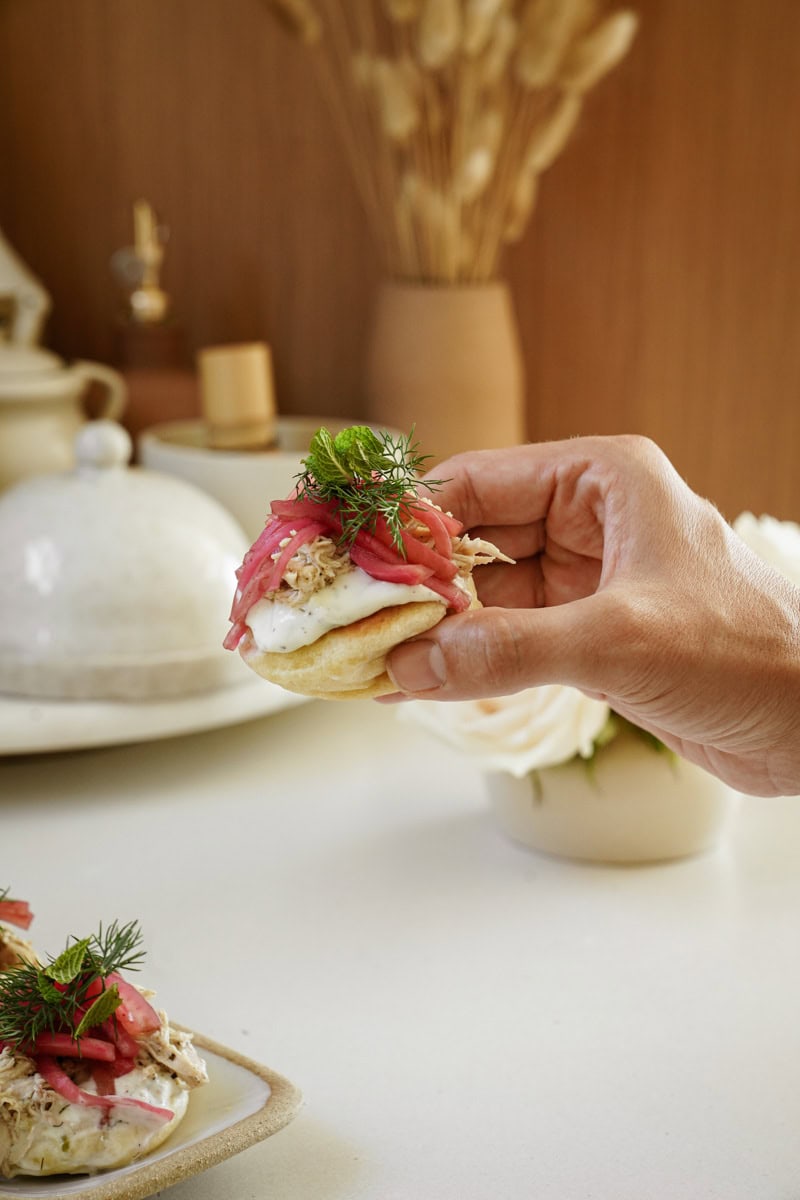 Hand holding slow cooker chicken breast on slider