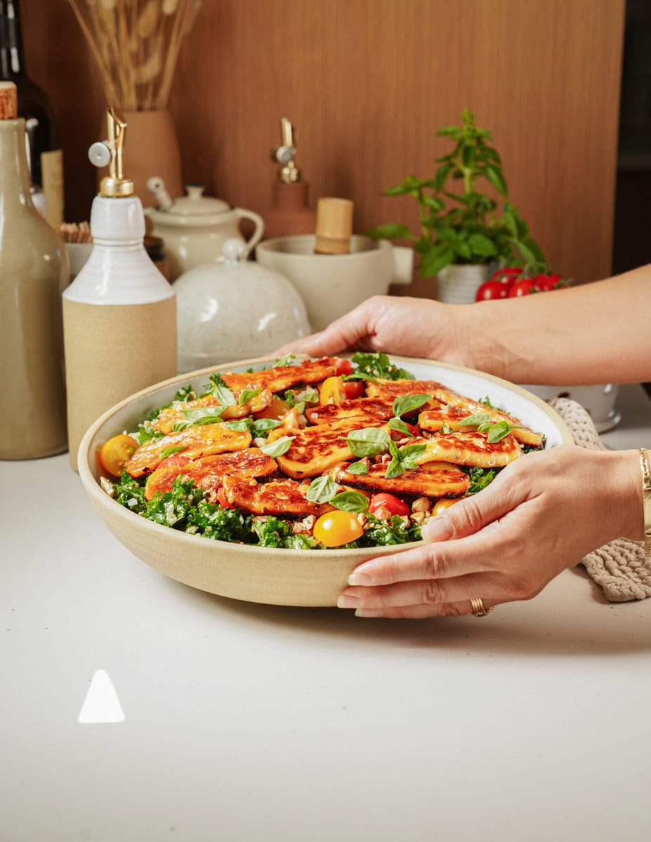 Hand placing the bowl of Halloumi Salad on a counter