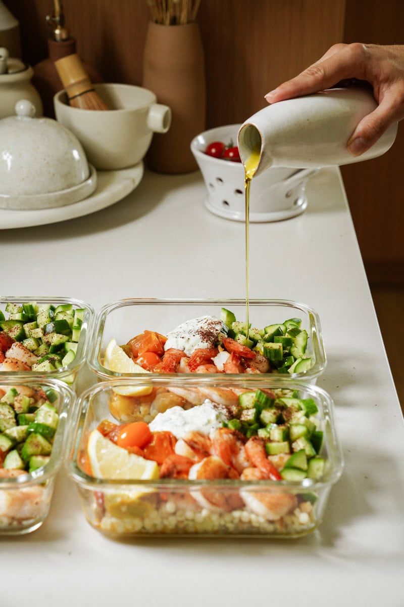 Dressing being drizzled on meal prep bowls