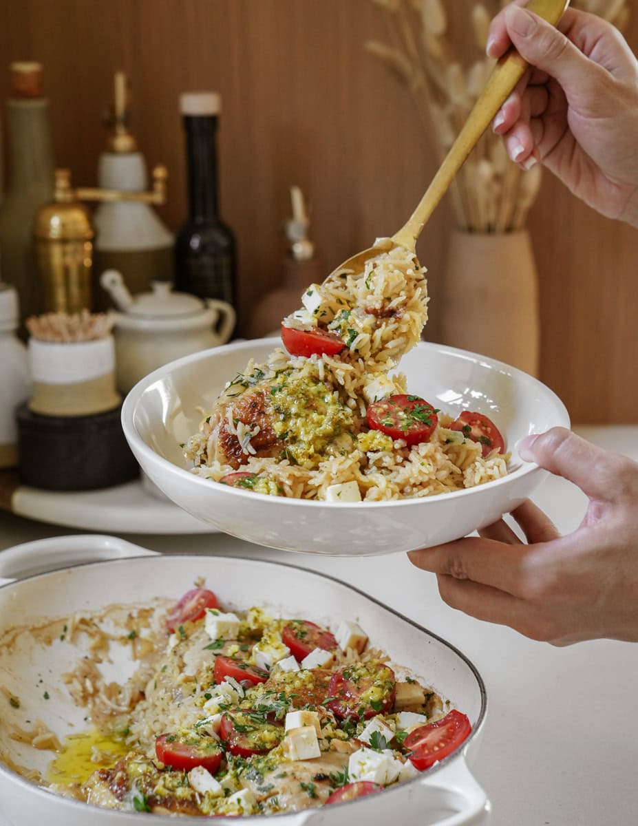 Person spooning oven baked chicken and rice into a bowl